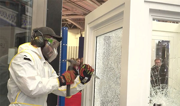 The LPCB security tester takes to the Selectaglaze secondary glazing with a paint scraper and hammer to try and penetrate the glass in a simulated attack test