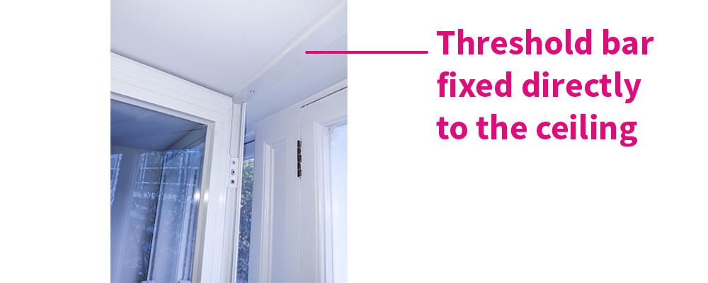 The flush threshold bar fixed to the ceiling to allow clearance for primary windows to open through secondary glazing